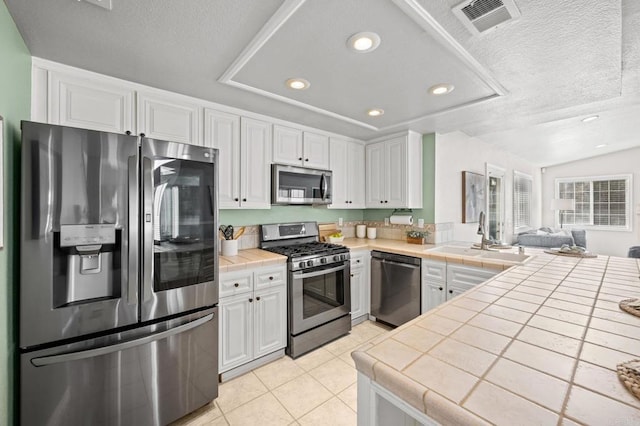 kitchen with white cabinets, appliances with stainless steel finishes, and tile countertops