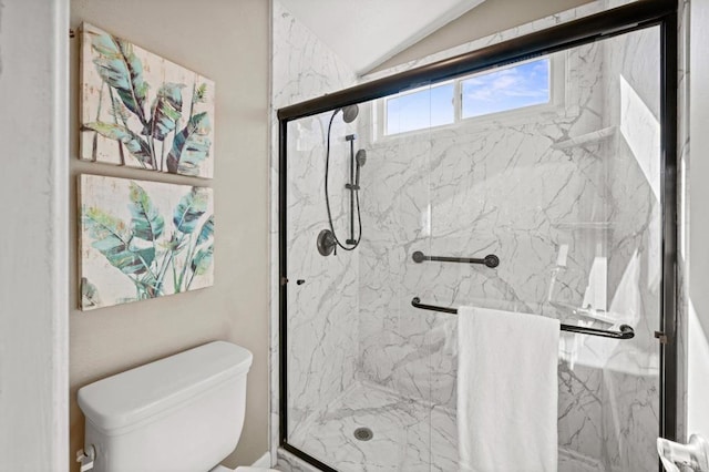 bathroom with toilet, a shower with shower door, and vaulted ceiling