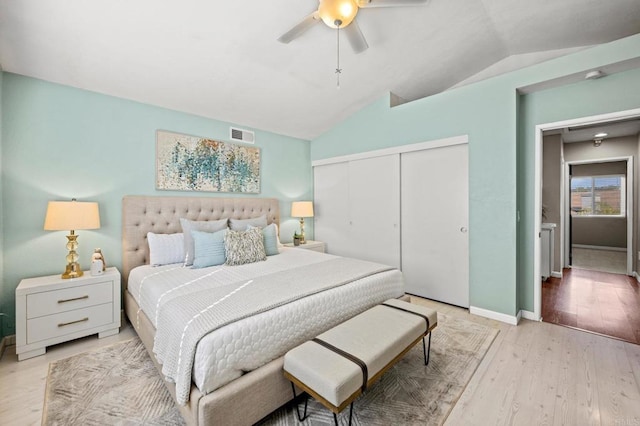 bedroom with vaulted ceiling, light wood-type flooring, ceiling fan, and a closet