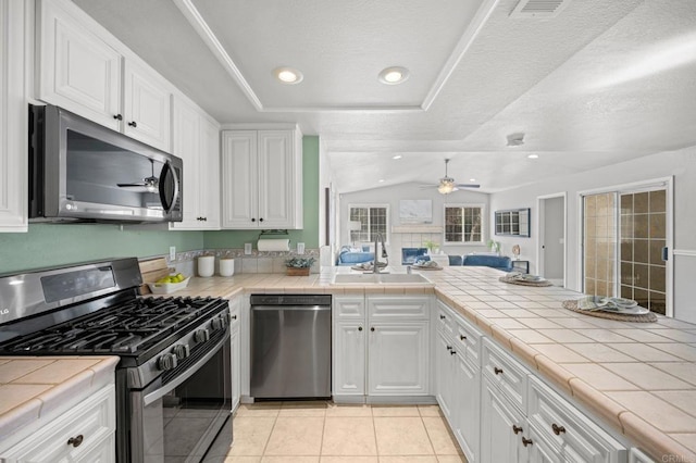 kitchen with sink, stainless steel appliances, white cabinetry, and tile counters