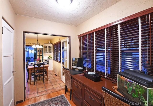 home office featuring an inviting chandelier, light wood-style flooring, and a textured ceiling