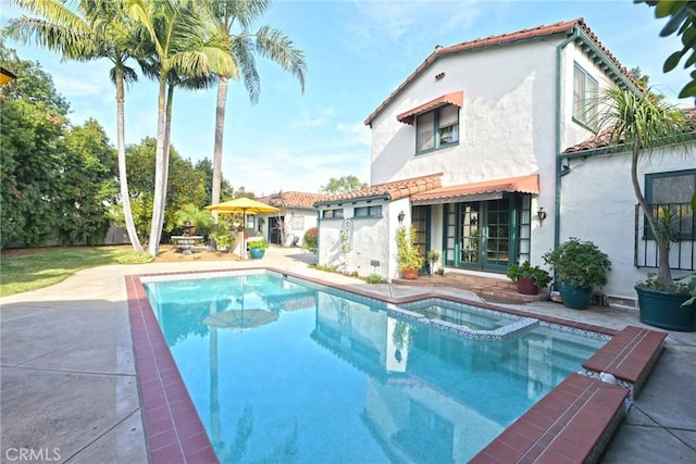 back of house with a pool with connected hot tub, a tile roof, stucco siding, a patio area, and french doors