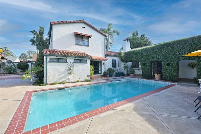 rear view of property with a tiled roof, a patio, a fenced in pool, and stucco siding