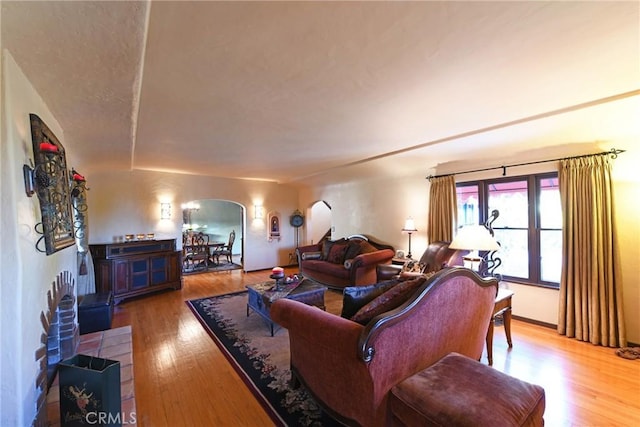 living area with arched walkways, wood finished floors, and a wood stove