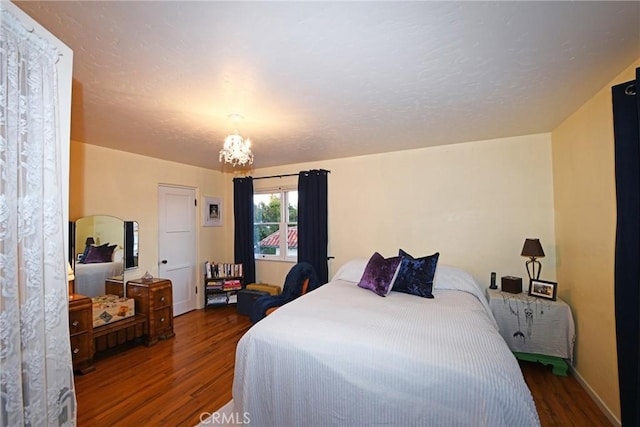 bedroom featuring an inviting chandelier, baseboards, and wood finished floors