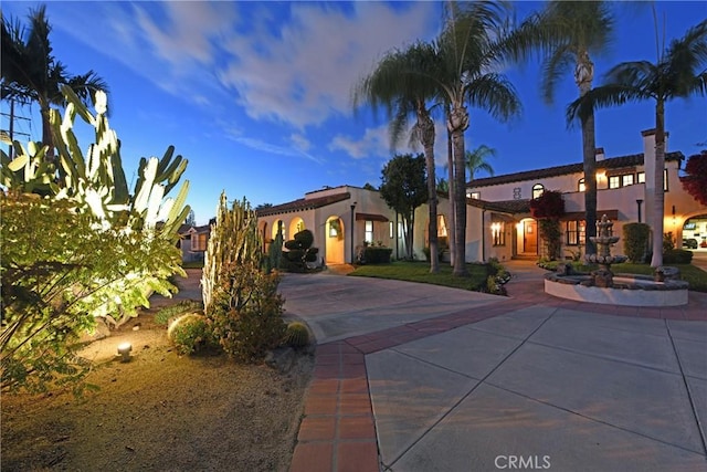 mediterranean / spanish house featuring curved driveway and stucco siding