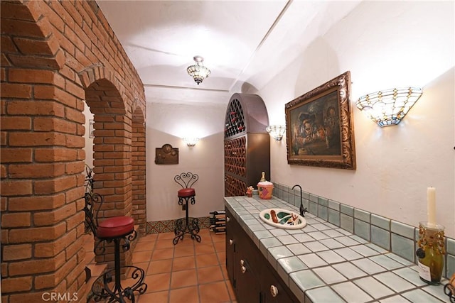 wine room with a sink, tile patterned floors, and brick wall