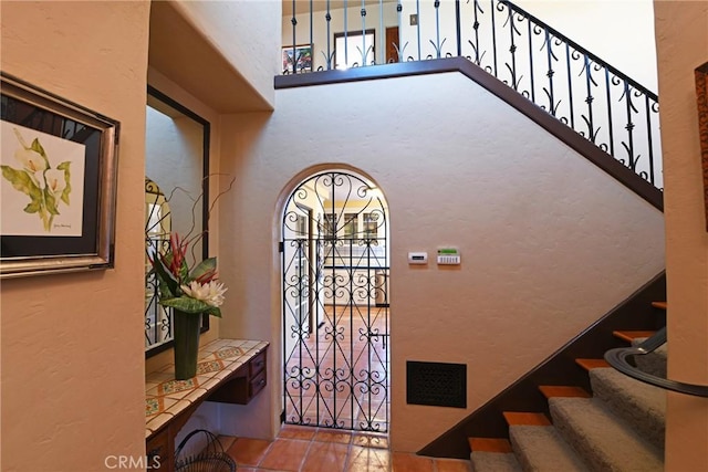 entryway with visible vents, stairway, and a towering ceiling