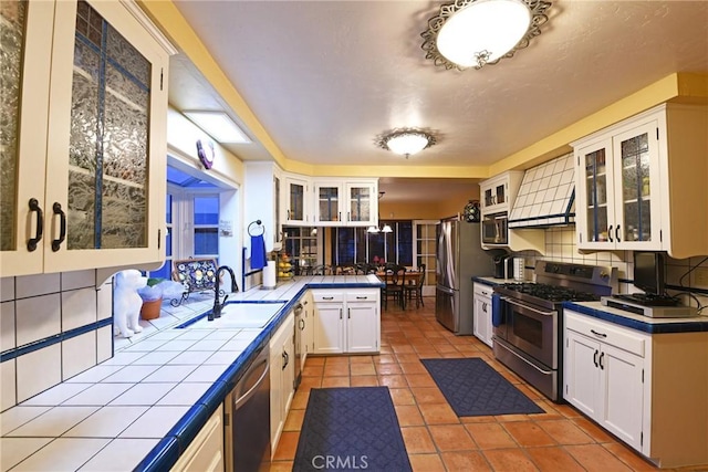 kitchen featuring backsplash, stainless steel appliances, tile countertops, and white cabinets