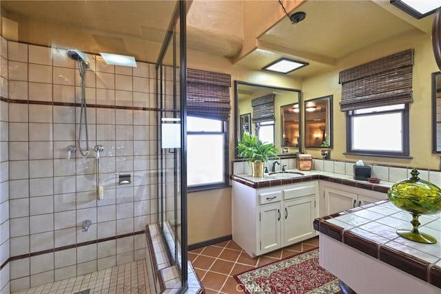 bathroom featuring a shower with shower door, tile patterned floors, a wealth of natural light, and vanity