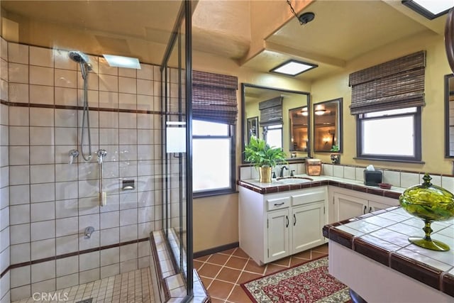 bathroom with tile patterned flooring, vanity, and a shower stall