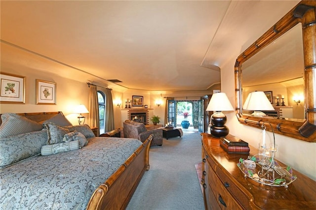 bedroom with visible vents, access to exterior, carpet, and a fireplace