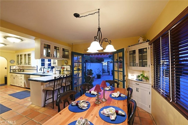 dining space featuring light tile patterned floors, a chandelier, and sink