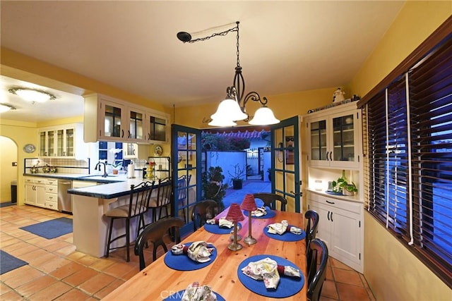 dining space featuring an inviting chandelier, arched walkways, and light tile patterned floors