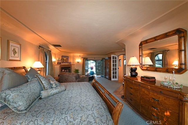 bedroom featuring carpet flooring, a lit fireplace, and visible vents