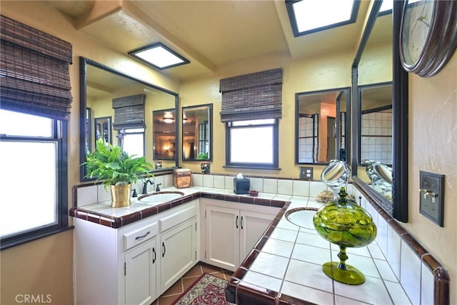 kitchen featuring kitchen peninsula, white cabinets, tile countertops, and sink