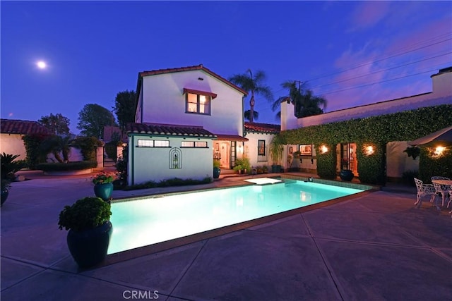 pool at dusk with a patio area