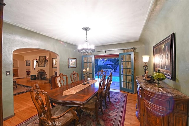 dining space featuring an inviting chandelier, arched walkways, and wood finished floors