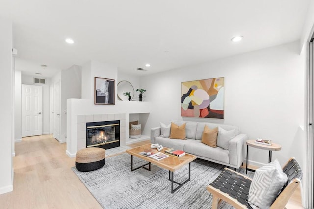 living room with a tile fireplace and wood-type flooring