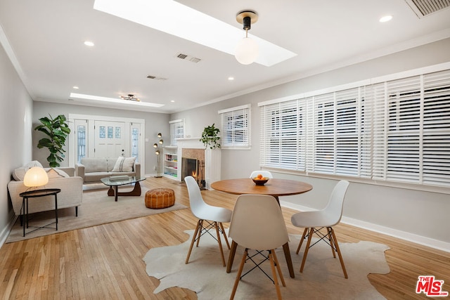 dining space featuring light hardwood / wood-style floors, crown molding, and a skylight