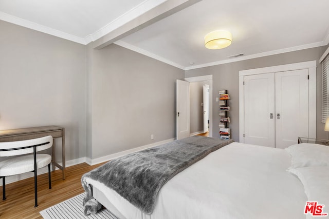 bedroom with ornamental molding, light hardwood / wood-style flooring, and a closet