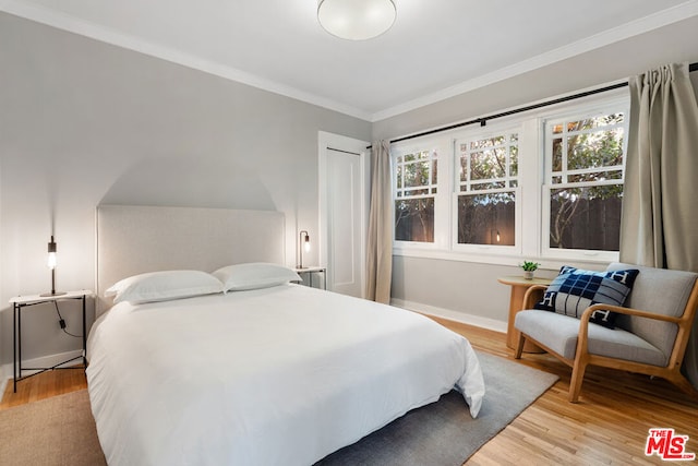 bedroom with a closet, light wood-type flooring, and crown molding