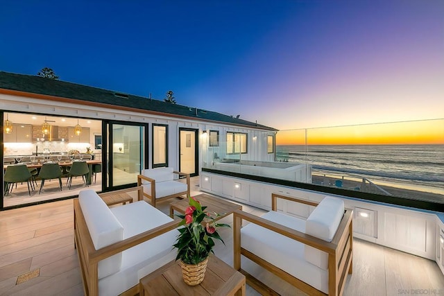 balcony at dusk with an outdoor hangout area and a water view