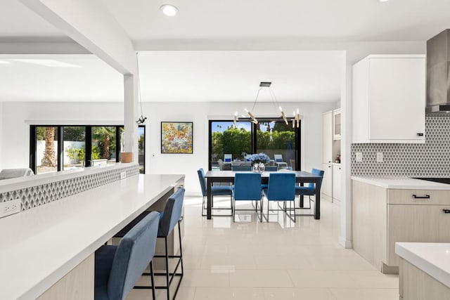 kitchen featuring an inviting chandelier, backsplash, light brown cabinetry, decorative light fixtures, and light tile patterned flooring