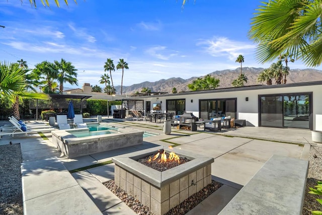 view of pool with an outdoor fire pit, a patio area, an in ground hot tub, and a mountain view