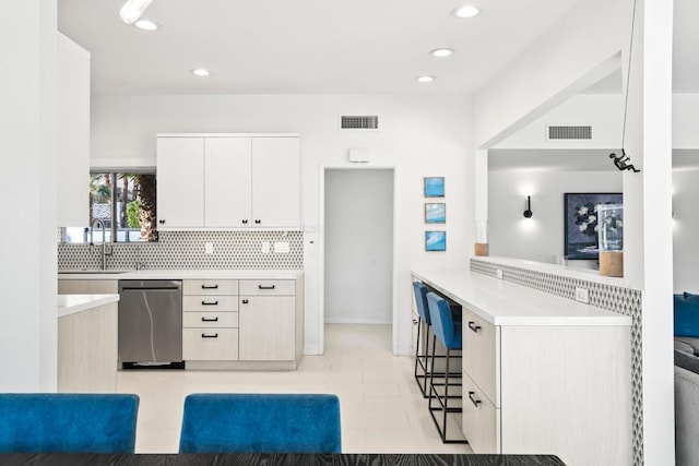 kitchen featuring sink, white cabinets, dishwasher, tasteful backsplash, and kitchen peninsula