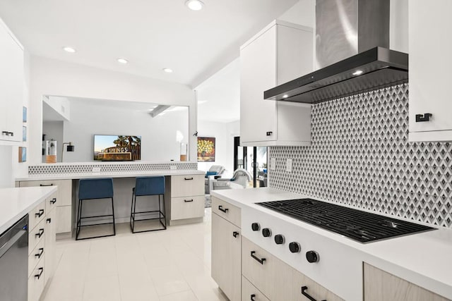 kitchen featuring white cabinetry, cooktop, stainless steel dishwasher, backsplash, and wall chimney range hood