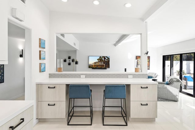 kitchen with light tile patterned floors, a kitchen bar, and tasteful backsplash