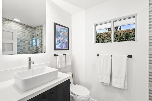 bathroom featuring toilet, a tile shower, and vanity