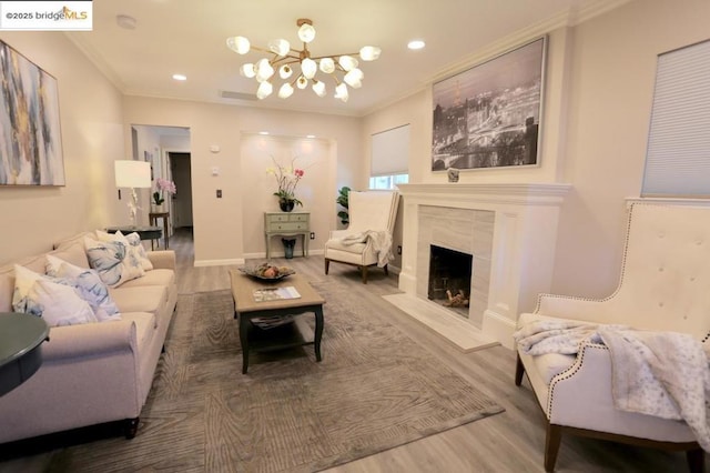 living room with a fireplace, hardwood / wood-style floors, an inviting chandelier, and ornamental molding