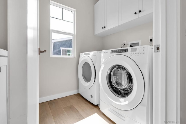 laundry area featuring washer and dryer, cabinets, and light hardwood / wood-style floors