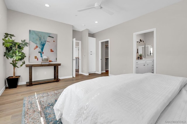 bedroom featuring ensuite bathroom, a closet, light wood-type flooring, a walk in closet, and ceiling fan