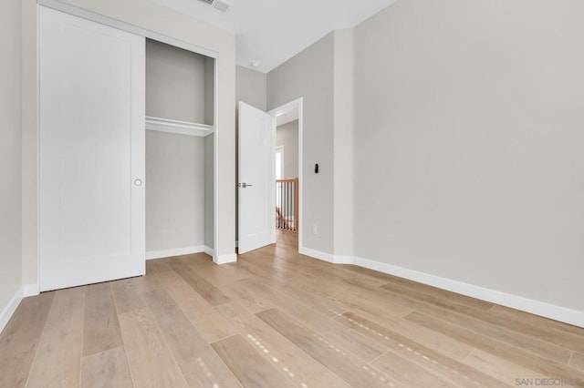 unfurnished bedroom with light wood-type flooring and a closet