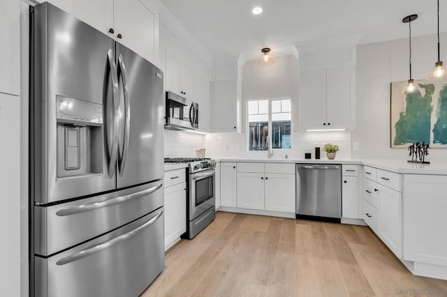 kitchen with appliances with stainless steel finishes, light hardwood / wood-style floors, white cabinetry, decorative light fixtures, and backsplash