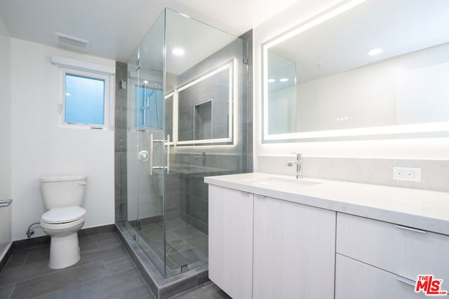 bathroom featuring toilet, tile patterned floors, a shower with shower door, and vanity