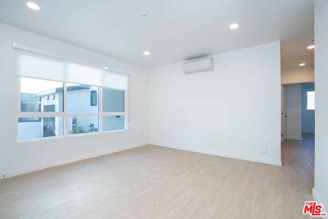 empty room with a wall mounted AC and light wood-type flooring