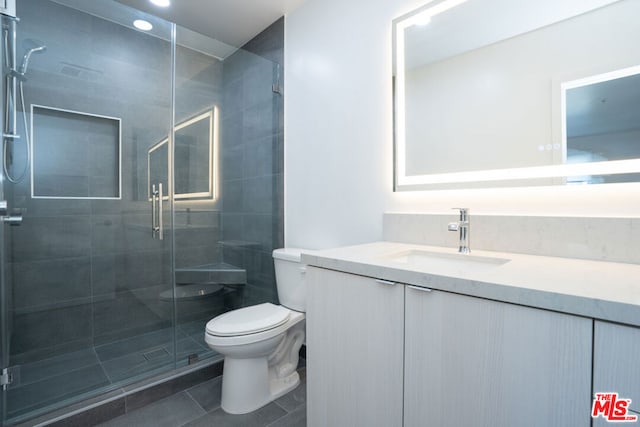 bathroom featuring toilet, tile patterned flooring, a shower with door, and vanity