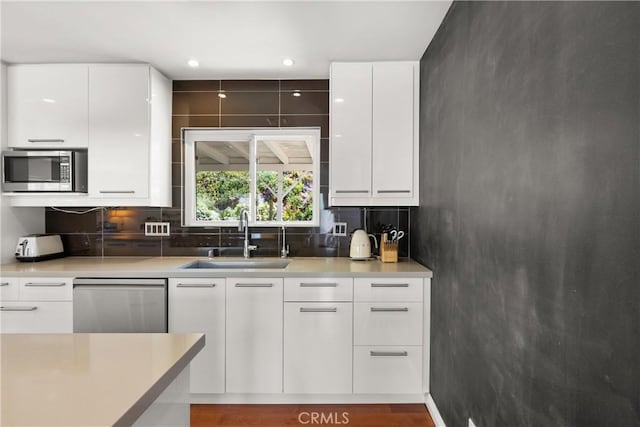 kitchen with stainless steel appliances, sink, white cabinets, decorative backsplash, and dark hardwood / wood-style flooring