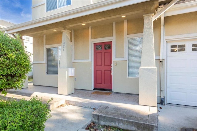 view of exterior entry featuring a garage and a porch