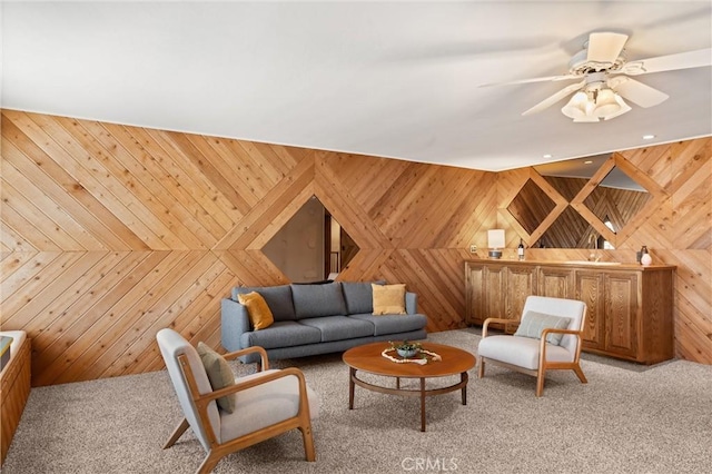 living room featuring ceiling fan, wooden walls, and light carpet