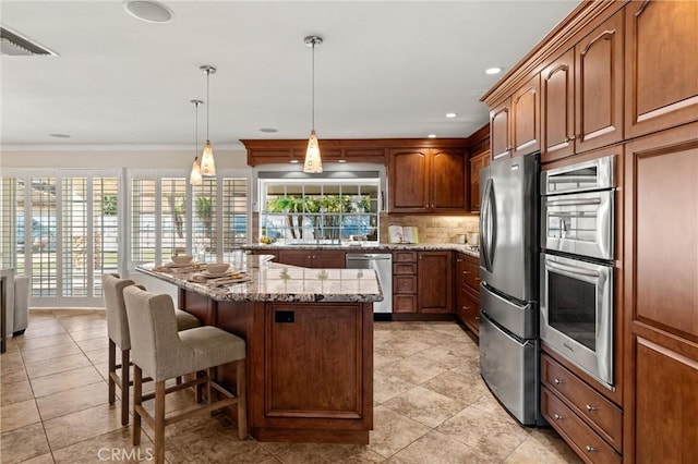 kitchen featuring a kitchen breakfast bar, stainless steel appliances, hanging light fixtures, light stone counters, and a kitchen island