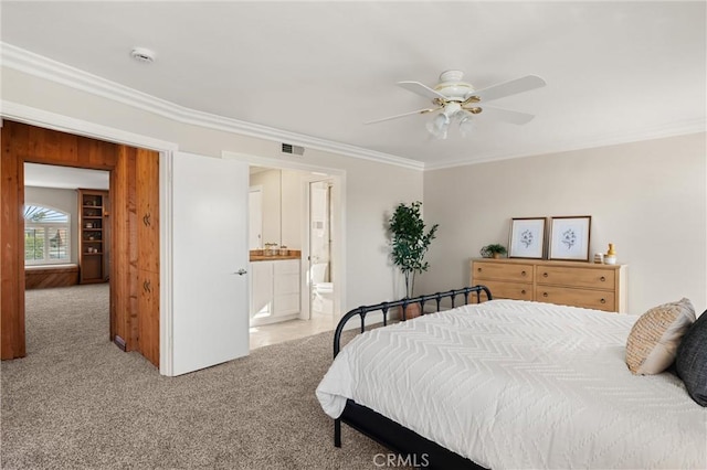 bedroom with ceiling fan, light colored carpet, ensuite bathroom, and crown molding