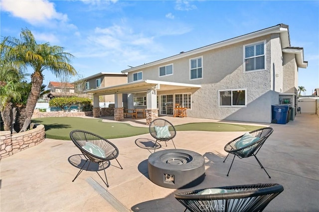 back of property with a patio and a fire pit