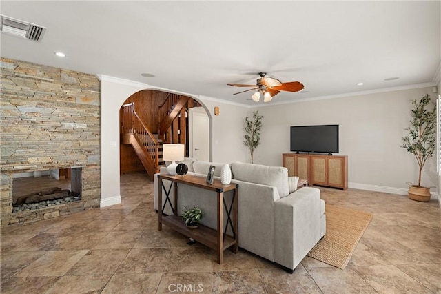 living room with ornamental molding, ceiling fan, and a stone fireplace