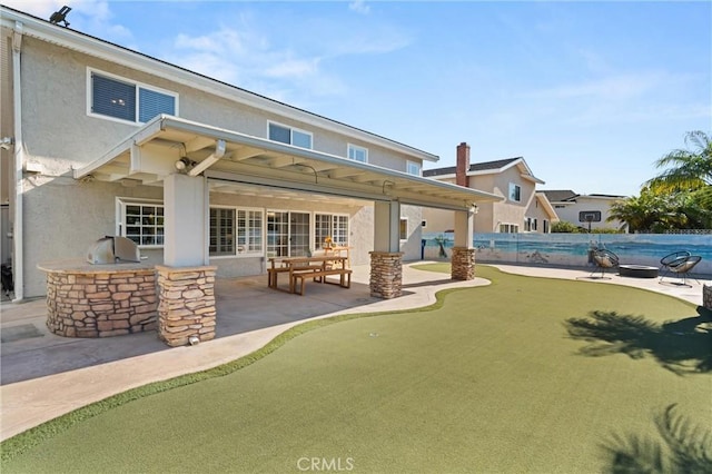 back of property with an outdoor kitchen and a patio