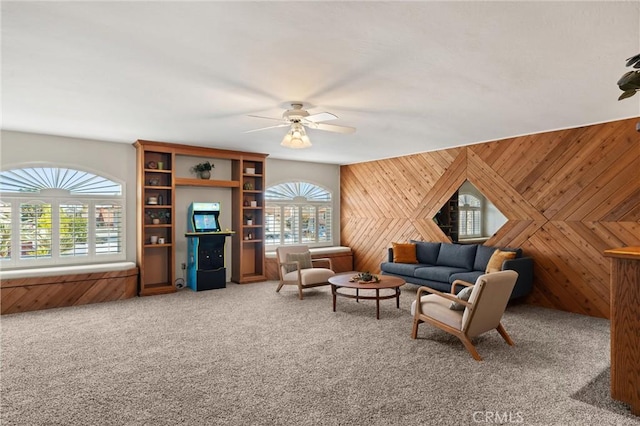 carpeted living room with ceiling fan and wooden walls